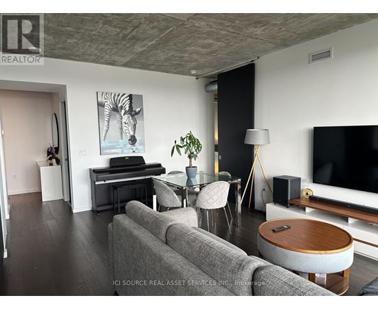 A living room with a grey couch, a wooden coffee table, and a television.