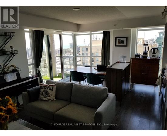 A living room with a grey couch and a piano.
