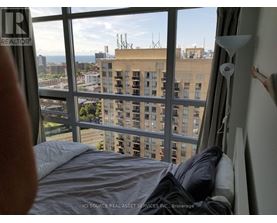 A bedroom with a large window overlooking a cityscape.