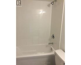 A white bathroom with a tub and toilet.