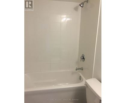A white bathroom with a tub and toilet.