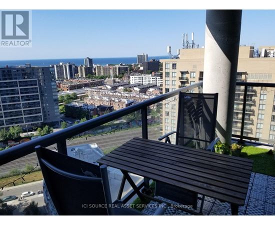A balcony with a table and chairs overlooking a cityscape.