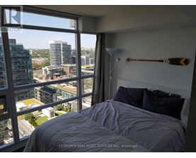 A bedroom with a large window overlooking a cityscape.