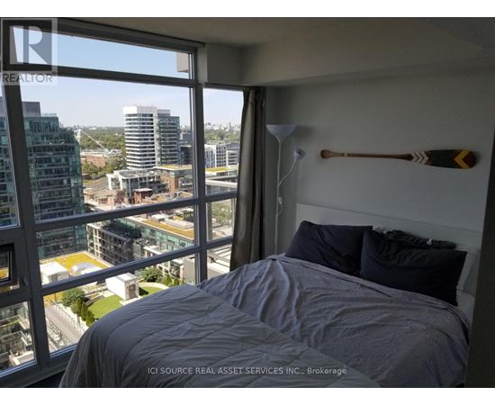 A bedroom with a large window overlooking a cityscape.