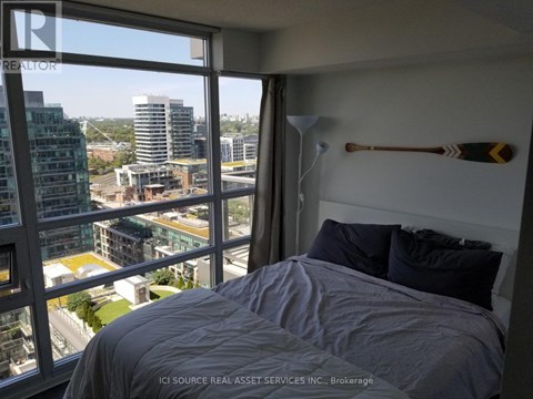 A bedroom with a large window overlooking a cityscape.