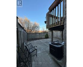 A black cooler sits on a patio with a chair and railing.