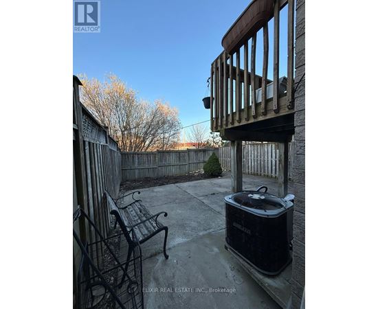 A black cooler sits on a patio with a chair and railing.