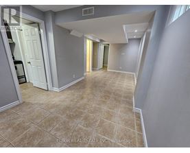 A spacious room with tiled flooring and a mix of grey and white walls.