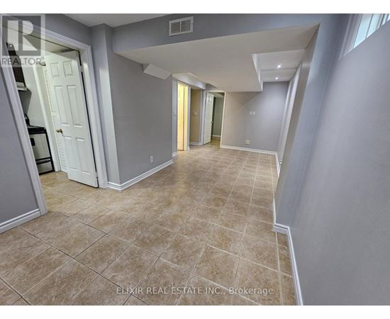 A spacious room with tiled flooring and a mix of grey and white walls.