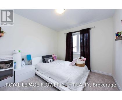 A bedroom with a white bed and a window with brown curtains.