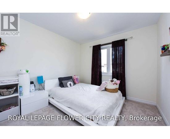 A bedroom with a white bed and a window with brown curtains.