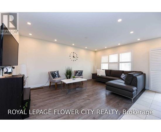 A living room with a black couch and a wooden floor.