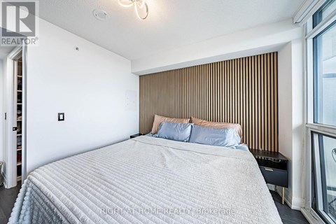 A bedroom with a large bed and a window with blinds.
