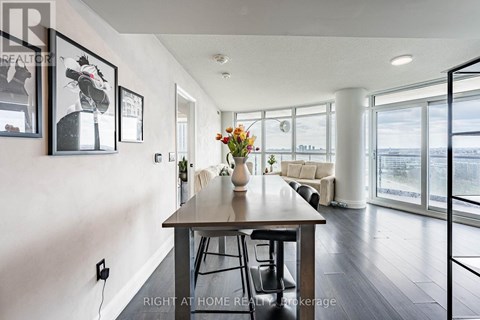 A dining room with a table and chairs and a vase of flowers on the table.