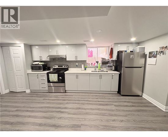 A kitchen with white cabinets and a grey floor.