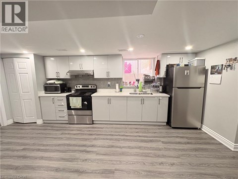 A kitchen with white cabinets and a grey floor.