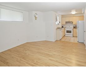 A kitchen with a white fridge and wooden floors.