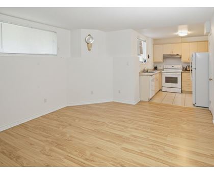 A kitchen with a white fridge and wooden floors.
