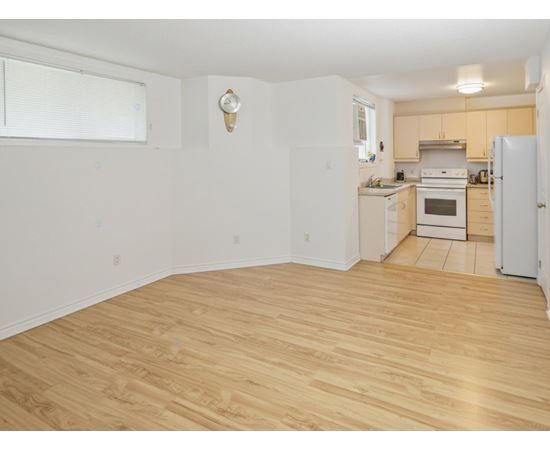 A kitchen with a white fridge and wooden floors.