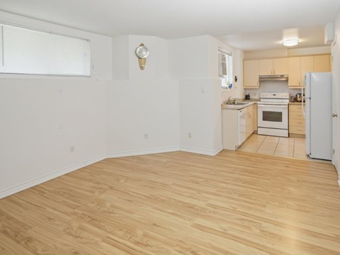 A kitchen with a white fridge and wooden floors.