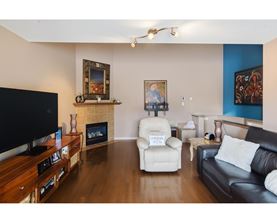A living room with a black couch, a white chair, and a television.