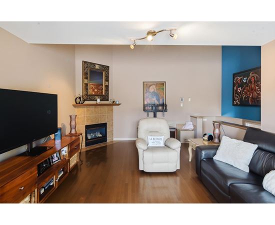 A living room with a black couch, a white chair, and a television.