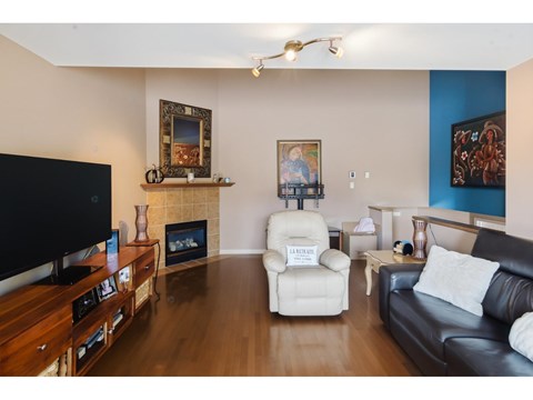 A living room with a black couch, a white chair, and a television.