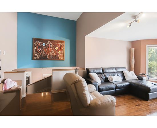 A living room with a blue wall and a painting hanging on it.