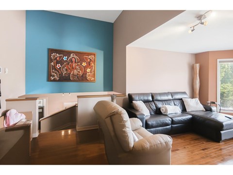 A living room with a blue wall and a painting hanging on it.