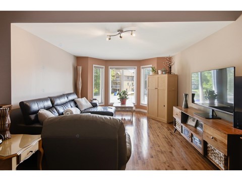 A living room with a black leather couch and a television.
