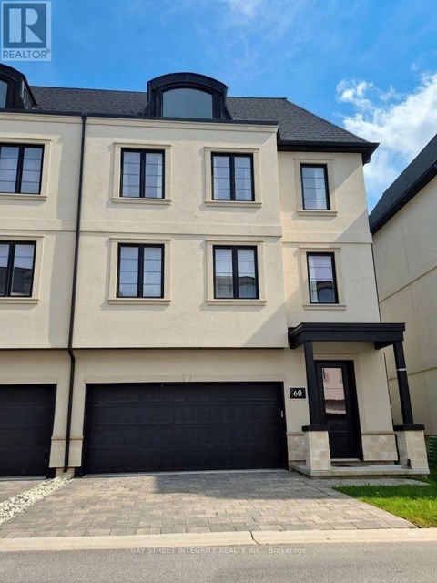A modern two-story building with a black garage door and a balcony on the second floor.