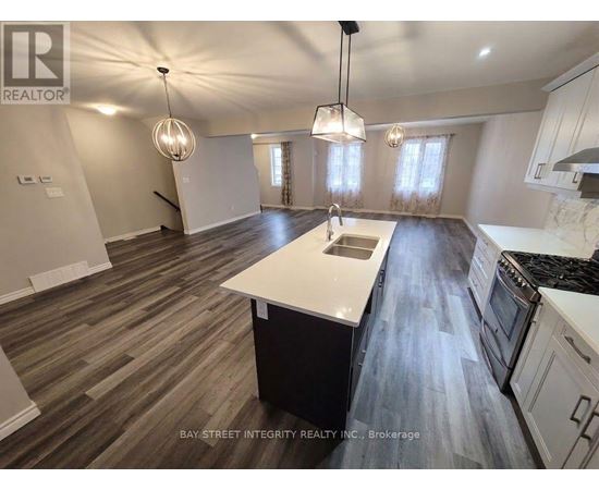 A spacious kitchen with wooden flooring and white appliances.