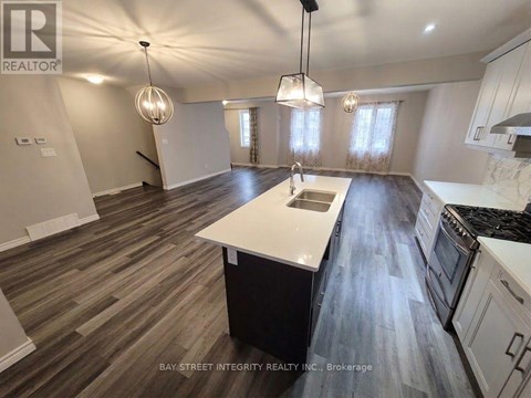 A spacious kitchen with wooden flooring and white appliances.