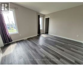 A spacious room with wooden flooring and a large window.