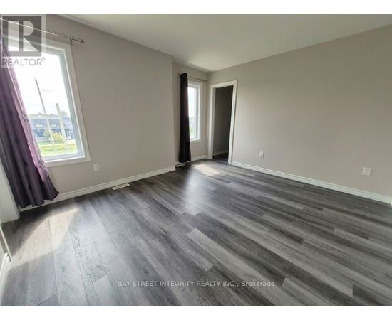 A spacious room with wooden flooring and a large window.