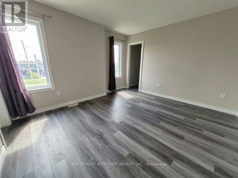A spacious room with wooden flooring and a large window.