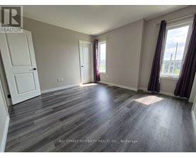 A room with wooden flooring and a large window with curtains.