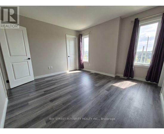 A room with wooden flooring and a large window with curtains.