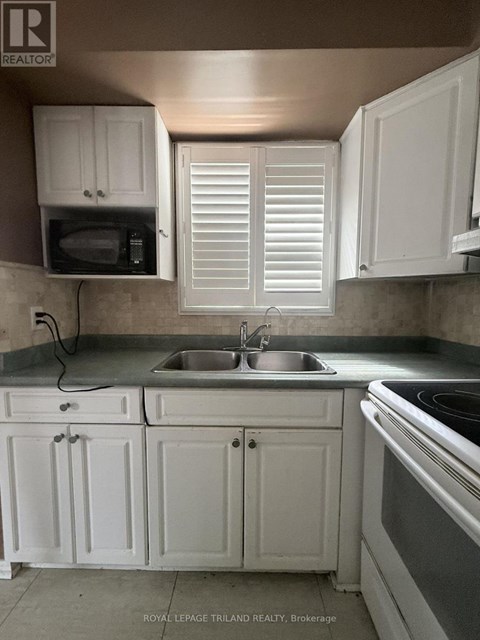 A kitchen with white cabinets and a stove top oven.