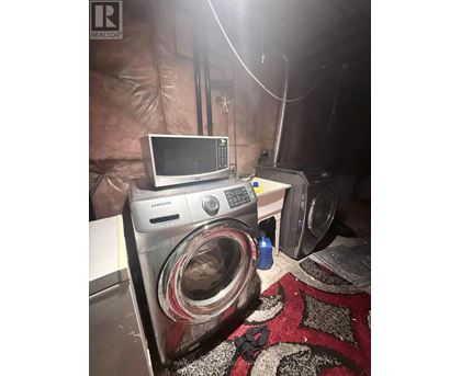 A washing machine is in a room with a microwave on top of it.