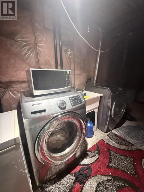 A washing machine is in a room with a microwave on top of it.