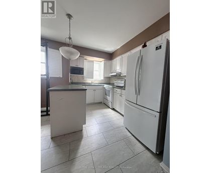 A kitchen with white appliances and a white island.