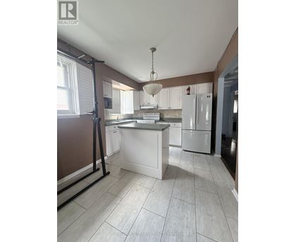 A kitchen with white appliances and a white island.