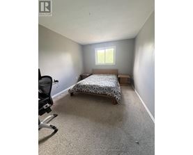 A bedroom with a bed, chair, and window.