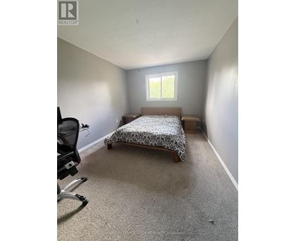 A bedroom with a bed, chair, and window.