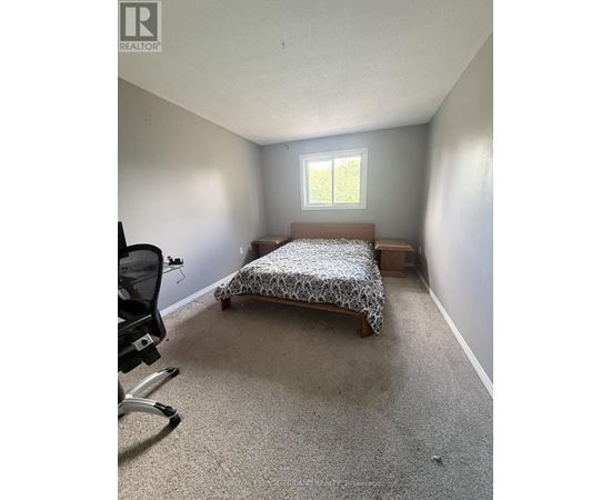 A bedroom with a bed, chair, and window.