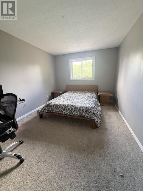 A bedroom with a bed, chair, and window.