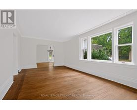 A room with wooden floors and white walls, with a doorway leading to another room.