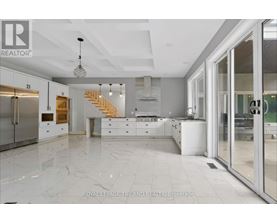 A spacious kitchen with marble flooring and a staircase in the background.