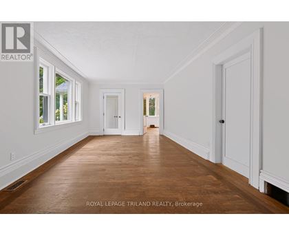 A spacious room with wooden floors and white walls.